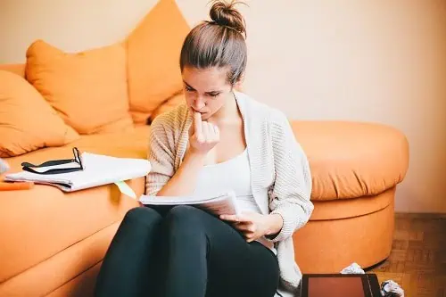 young woman biting nails studying