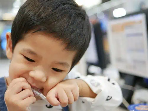 boy uses teeth to open something