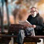 older man reading on park bench